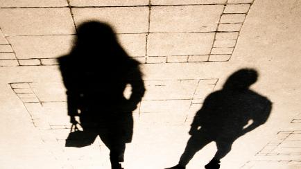 Silhouette shadow of a woman and a man on city sidewalk in sepia black and white
