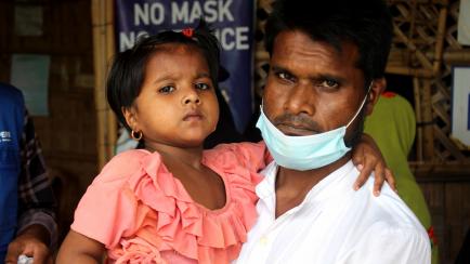Un refugiado rohingya, que llegó a Bangladesh después de la persecución de Myanmar hace cinco años, lleva a su hija al centro de salud en Cox's Bazar.