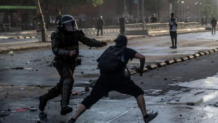 Un antidisturbios trata de atrapar a un manifestante durante los disturbios en Chile. 