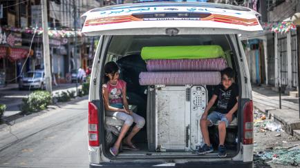 Dos niños palestinos, en una furgoneta con sus pertenencias rescatadas de su casa en Gaza después de que la destruya un ataque israelí el 17 de mayo de 2021.
