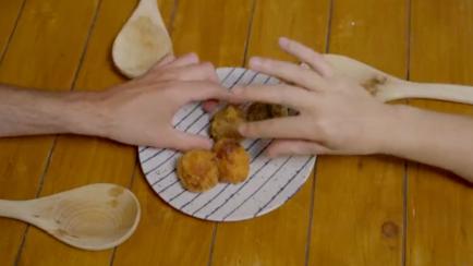 Dos personas cogiendo croquetas de un plato.