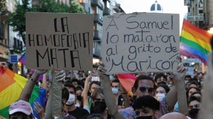 Dos personas sostienen sendas pancartas durante una manifestación en Madrid contra la homofobia y en repulsa por el asesinato de Samuel Luiz.