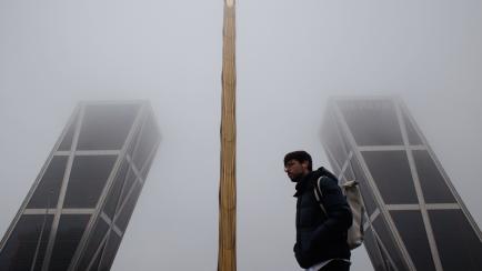 Un hombre camina en Madrid entre la niebla. 