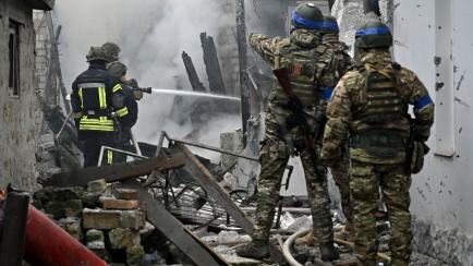Policías ucranianos y bomberos trabajando en una casa en llamas tras del bombardeo ruso en la ciudad de Jersón, este domingo.