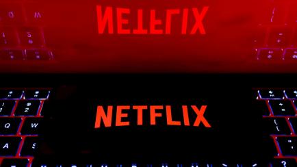 Logotipo de Netflix en la pantalla de un móvil reflejado en la de un portátil