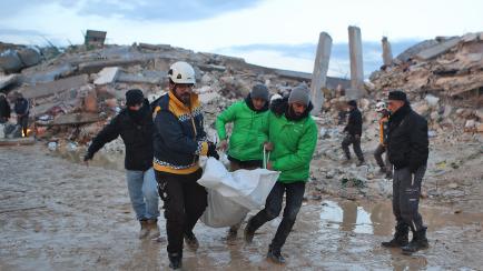 Rescatadores sirios portan un cuerpo rescatado de los escombros en la ciudad de Sarmada, ayer.