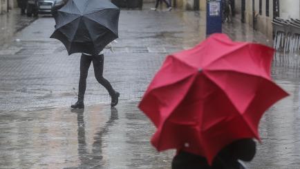 Dos personas con paraguas bajo la lluvia en Valencia, este lunes.
