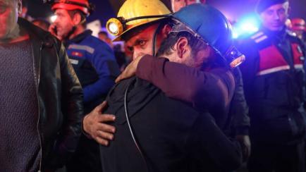 Dos operarios de emergencias se abrazan durante las labores de rescate en Turquía