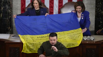 Kamala Harris y Nancy Pelosi sostienen una bandera ucraniana firmada por soldados y regalada por Volodimir Zelenski en su visita al Capitolio, el pasado diciembre.