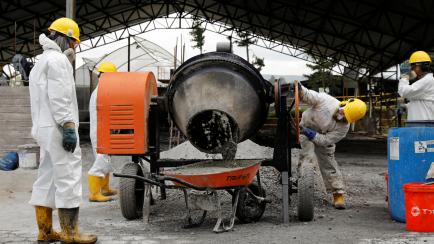 Trabajadores mezclando pasta de coca con los materiales necesarios para hacer hormigón, en una obra.