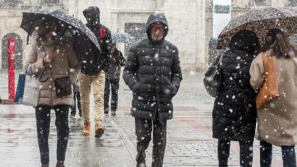 Varias personas caminan por la calle mientras nieva en Burgos.