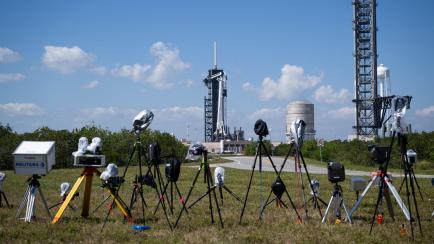 Fotografía cedida por la NASA donde se aprecian una cámaras instaladas por miembros de los medios informativos frente al cohete Falcon 9 de SpaceX con la nave espacial Dragon en la parte superior el sábado 25 de febrero en la plataforma de lanzamiento 39A en el Centro Espacial Kennedy de la NASA en Florida