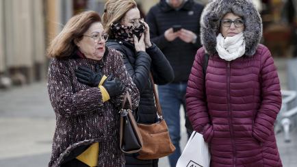 Tres mujeres protegidas contra el viento y el frio pasean este lunes por el centro de Valencia.