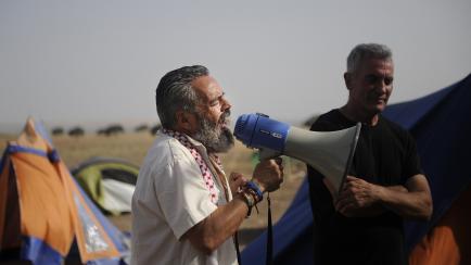 A member of the regional parliament for the United Left party in Andalucia, Juan Manuel Sanchez Gordillo, speaks on August 9, 2012 to militants camping near the southern Sapnish town of Osuna. The Spanish government issued arrest warrants on August 8 for left-wing activists who looted supermarkets and filled trolleys with food to give to the needy in the recession. The Interior Ministry issued the warrant for the group, including its leader Sanchez. The group raided two supermarkets in Andalucia, a region particularly hard hit by a recession brought on by the collapse of its major construction industry. Andalucia's unemployment rate is nearly 34 percent.       AFP PHOTO / CRISTINA QUICLER        (Photo credit should read CRISTINA QUICLER/AFP/GettyImages)