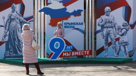 Una mujer se fotografía ante una instalación que conmemora los nueve años de Crimea en manos de Rusia. Los lemas dicen: "Primavera de Crimea. Hemos estado juntos durante 9 años".