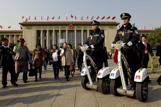 Policías chinos hacen guardia sobre vehículos eléctricos frente al Gran palacio del Pueblo