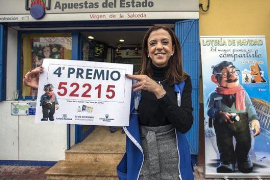 La propietaria de la administración número uno de las Torres de Cotillas (Murcia) Fuensanta Ortíz, muestra el cartel con el cuarto premio de la Lotería de Navidad, el 52215, del que han vendido 15O décimos.
