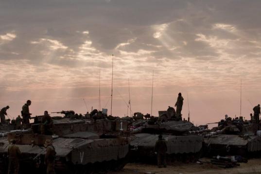 Soldados israelíes permanecen sobre sus tanques al amanecer en la frontera con la Franja de Gaza 