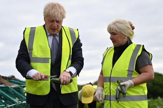 Johnson, a punto de cortar un pepino recogido de una granja de Cornwall por él mismo. Y bajo la atenta mirada de preocupación de su acompañante.