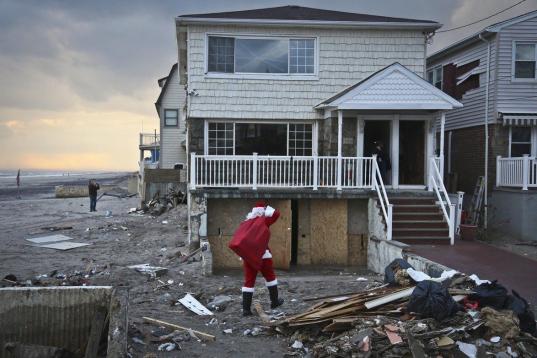 En esta foto del martes 18 de diciembre de 2012, el consultor político Michael Sciaraffo, disfrazado de Santa Claus, lleva juguetes a hogares afectados por el huracán Sandy en el barrio Bell Harbor de Nueva York. (AP Foto/Bebeto Matthews)