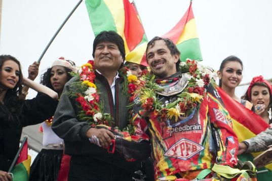 El presidente boliviano Evo Morales, izquierda, estrecha la mano del piloto boliviano Juan Carlos Salvatierra al término de la séptima etapa del Rally Dakar en Uyuni, Bolivia, el domingo 12 de enero de 2014. (AP Foto/Victor R. Caivano)