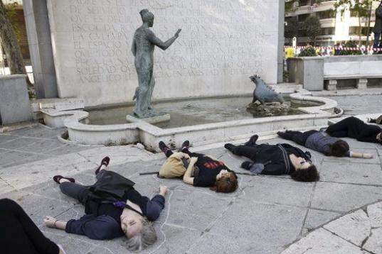 En la plaza de la Cibeles, en el lateral de la fuente, la asociación "Generando Arte" ha colocado flores y ha representado el drama de la violencia machista con varias mujeres tumbadas en el suelo. 