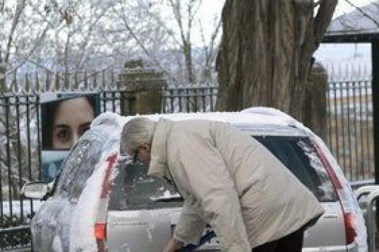 Un hombre quita la nieve de su coche en Segovia. Todas las provincias de Castilla y León, salvo Valladolid, están en aviso por nevadas o frío intenso que llegará hasta los 6 grados bajo cero en zonas de montaña.