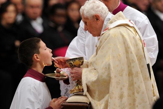 Pope Benedict XVI (R) gives the communion to an altar boy as he celebrates Christmas mass at St. Peter's Basilica in Vatican City on December 24, 2011, to mark the nativity of Jesus Christ. Pope Benedict XVI hailed Christ's humility, urging the ...