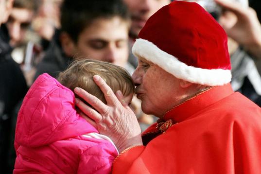 Vatican City, VATICAN CITY STATE:  Pope Benedict XVI wearing a Camauro, a red velvet hat with white ermine trim used by popes in the 12th century, kisses a baby as he arrives on St Peter's square at the Vatican to preside over his weekly general...