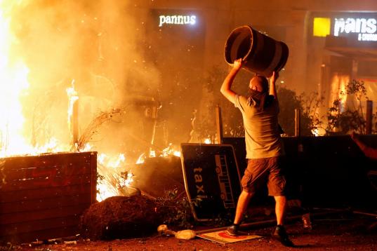 Un manifestante radical lanza una papelera al fuego