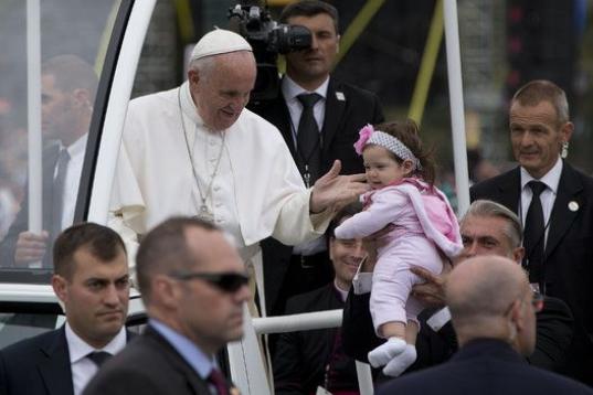 Pope Francis looks to a baby that he just kissed as he pauses in the popemobile during a parade along Benjamin Franklin Parkway in Philadelphia, Sunday, Sept. 27, 2015, on his way to celebrate mass. (AP Photo/Carolyn Kaster)