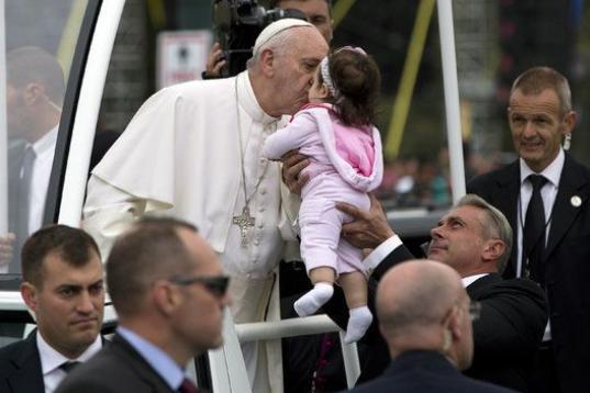 Pope Francis kisses a baby as he pauses in popemobile during a parade along the Benjamin Franklin Parkway in Philadelphia, Sunday, Sept. 27, 2015, on his way to celebrate Mass. (AP Photo/Carolyn Kaster)
