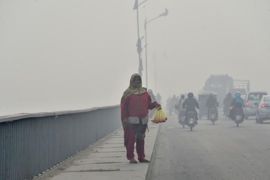A woman sells rose petals on a bridge amid the heavy smog condition in Lahore on November 21, 2019. (Photo by Arif ALI / AFP) (Photo by ARIF ALI/AFP via Getty Images)