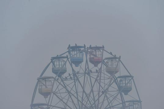 Birds sit on a ferris wheel amid heavy smog conditions in Lahore on November 21, 2019.   (Photo by Arif ALI / AFP) (Photo by ARIF ALI/AFP via Getty Images)