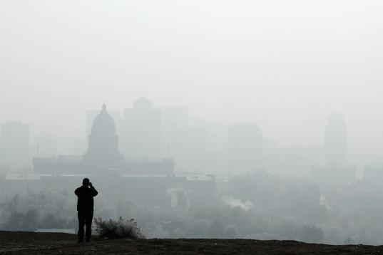 A man stops to take a picture of the Utah State Capitol (L) and buildings that are shrouded in smog in downtown Salt Lake City, Utah, U.S. December 12, 2017. Sometimes during the winter, temperature inversions form in the Salt Lake Valley, when ...