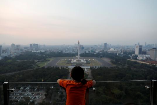 A girl looks on National Monument (Monas) as smog covers the capital city of Jakarta, Indonesia, July 4, 2019. REUTERS/Willy Kurniawan