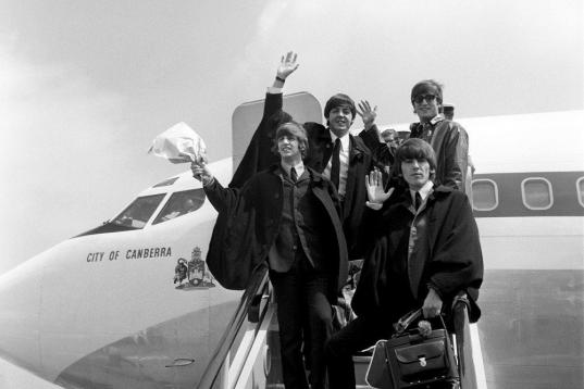 The Beatles, wearing cape-type coats, on the steps of the plane on arrival at London Airport from their Australian tour. At a Press Conference at the airport Lennon denied a rumour that he was leaving the group.