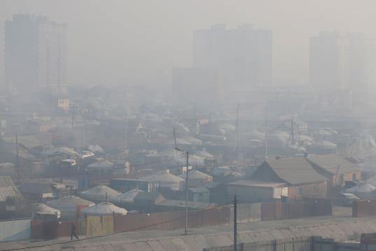 A man walks amid smog as smoke rises from chimneys in Sukhbaatar district of Ulaanbaatar, Mongolia January 31, 2019. Picture taken January 31, 2019. REUTERS/B. Rentsendorj