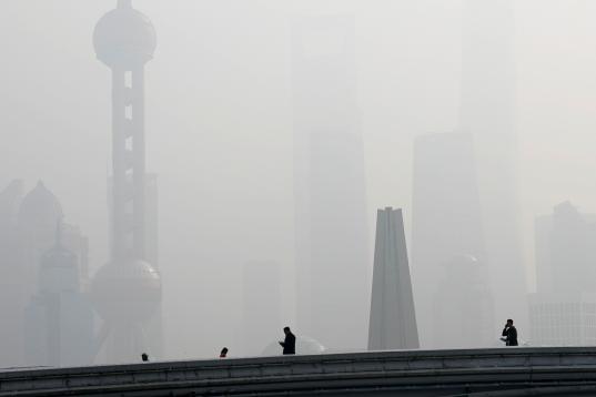 People walk on a bridge in front of the financial district of Pudong, which is covered in smog, during a polluted day in Shanghai, China November 28, 2018. REUTERS/Aly Song       TPX IMAGES OF THE DAY