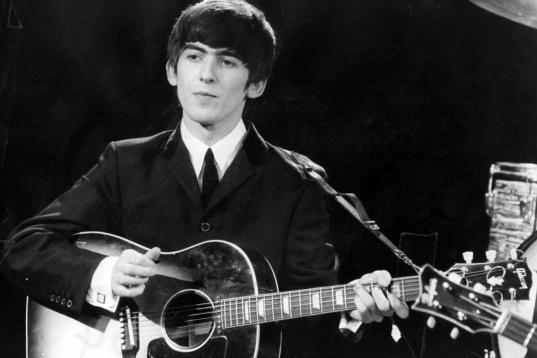 3rd December 1963:  Guitarist and singer George Harrison (1943 - 2001) of the popular Merseybeat group The Beatles, performing during a live concert.  (Photo by Fox Photos/Getty Images)