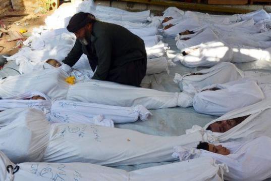 Un hombre coloca el cuerpo de un bebé entre otros cadáveres, antes de un entierro masivo en Ghouta, un barrio de Damasco donde se sospecha que las tropas del Gobierno atacaron con armas químicas en el verano de 2013. Fue una "línea roja" tra...