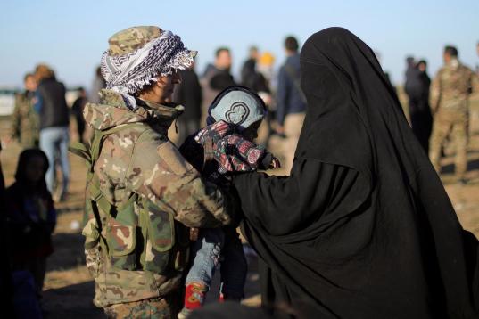 Una miliciana kurda atiende a una de las civiles rescatadas de la ciudad siria, junto a su bebé. 