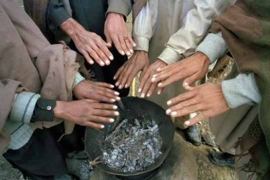 Refugiados del campamento ubicado en el pueblo de Bateela, en Pakistán, se juntan para calentar sus manos en una hoguera común.