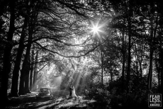 "La luz colándose entre los árboles crea una atmósfera de otro mundo. Como si estuvieran tomándose un descanso después de un paseo en coche, la pareja se pierde junta en este aislado y mágico mundo. Los rayos de sol y el blanco y negro hac...