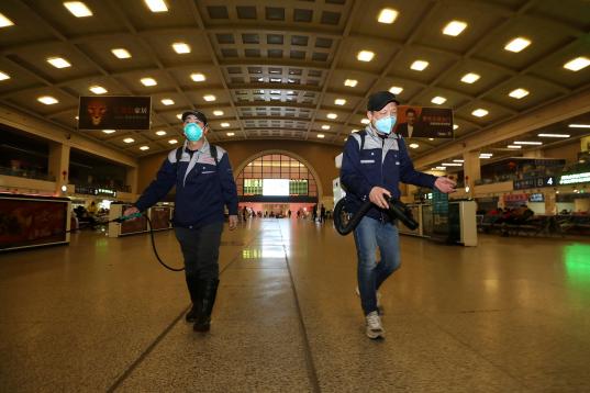 Dos trabajadores desinfectan la estación de Wuhan