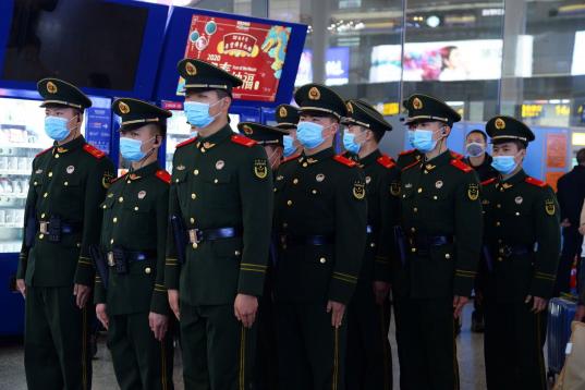 Agentes de policía vigilan una de las estaciones de tren en China, todos ellos con máscaras para evitar contagios