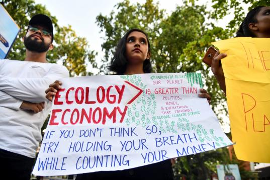 Una joven sostiene una pancarta mientras participa en una protesta contra la inacción gubernamental hacia el colapso climático y la contaminación ambiental en la India. 