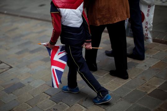 Un niño pasea por la calle principal de Gibraltar con una bandera del Reino Unido. 