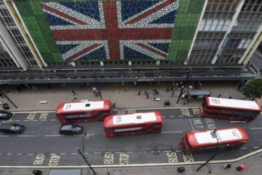 Peatones caminan por Oxford Street donde se ha colocado una bandera británica en la fachada de unos grnades almacenes en Londres