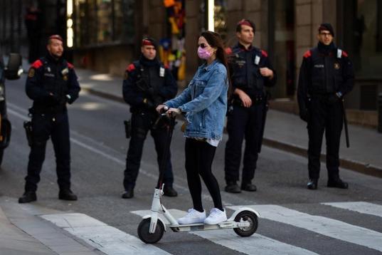 Una joven circula con su patinete en los aledaños de la plaza Sant Jaume, cuyos accesos se ven restringidos por el dispositivo de seguridad desplegado desde primera hora de la mañana ante el Palau de la Generalitat.